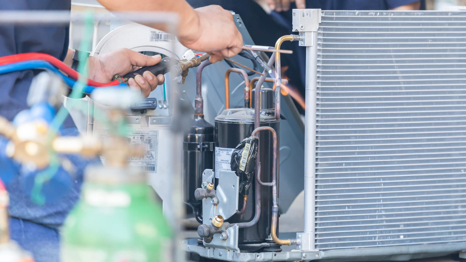 Hands servicing components inside an air conditioning unit